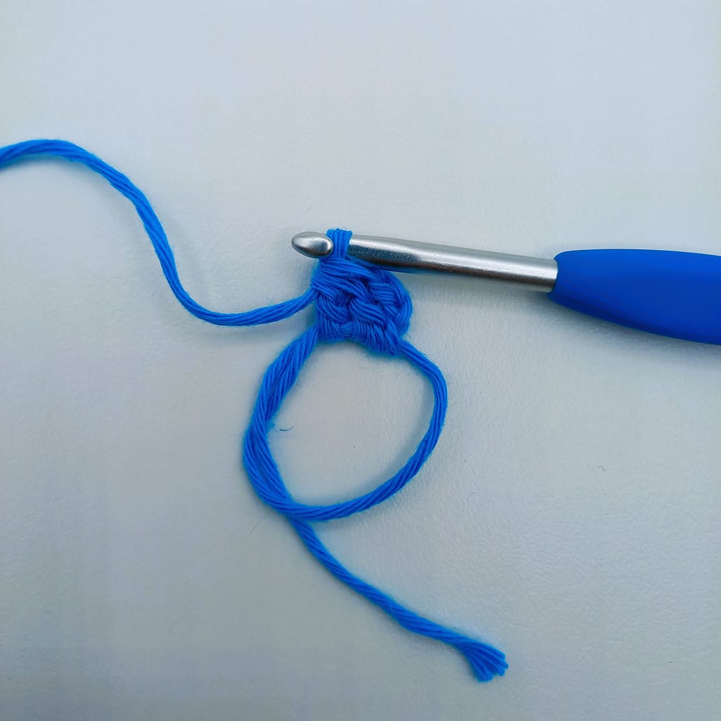 completed crochet bobble stitch in blue yarn on a blue crochet hook