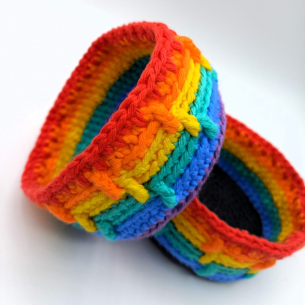 2 rainbow crochet baskets, one on its side to better display the texture of the spike stitches