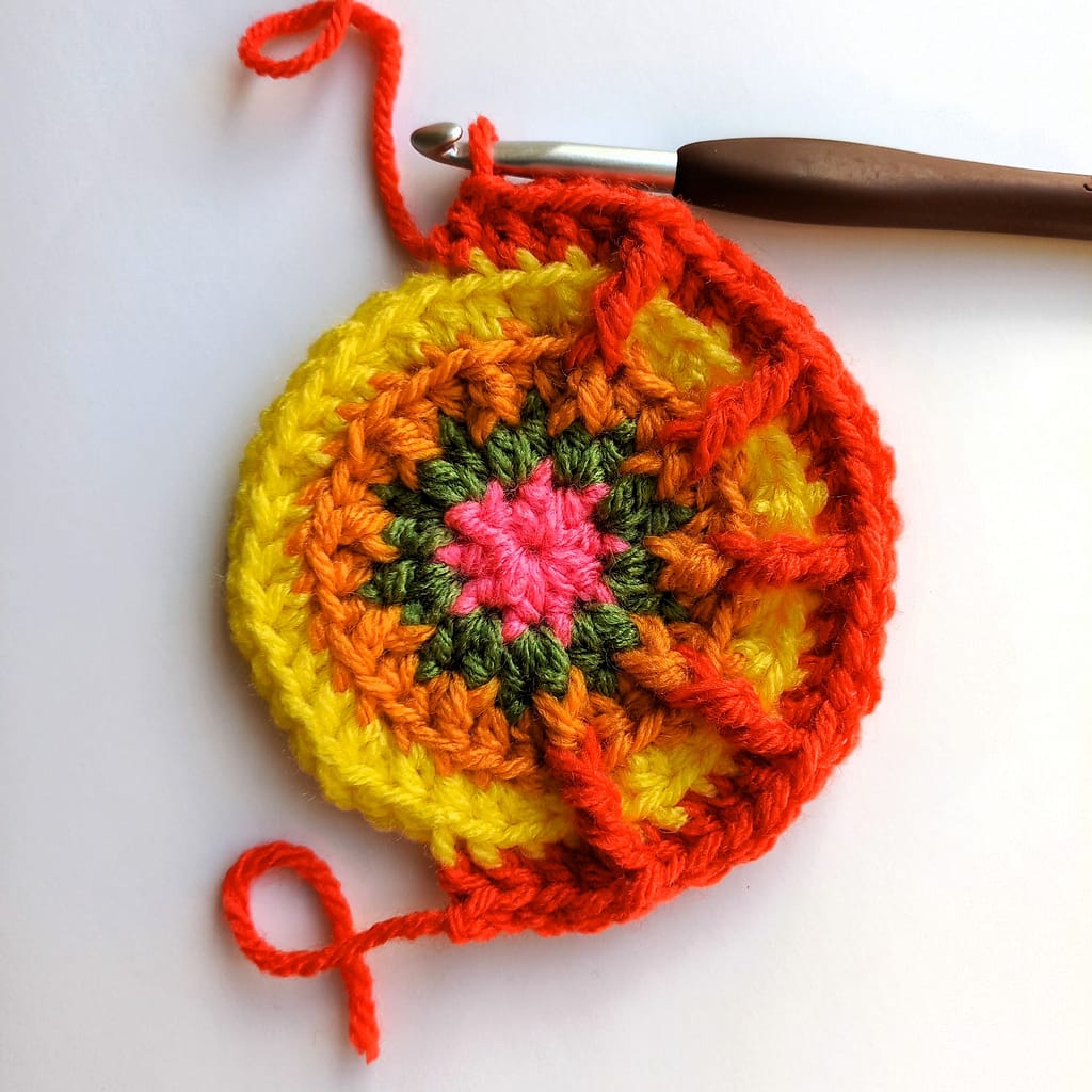 a small crochet cricle in progress with front post stitches being worked by the crochet hook