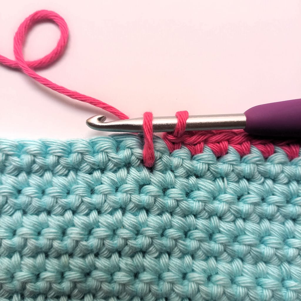 third step of single crochet spike stitch where yarn is lengthened to level of current round or row