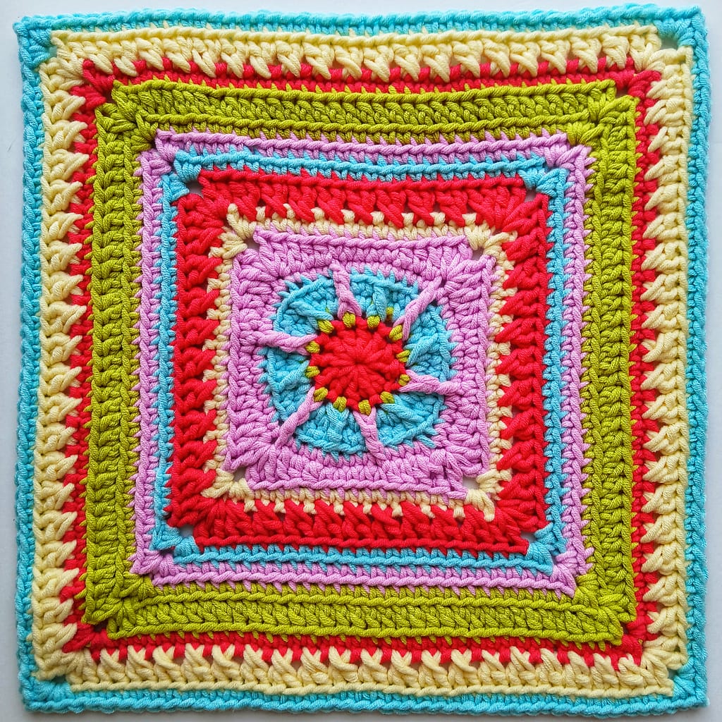 A flat lay of the completed granny square the instructions for which are in this blog post - made in red, green, pink, blue and cream yarns