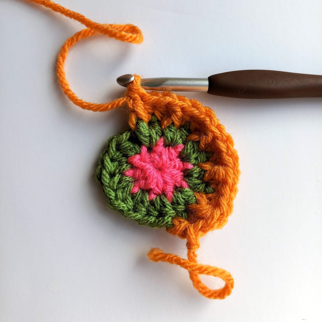 a small crochet circle in progress with working hook attached