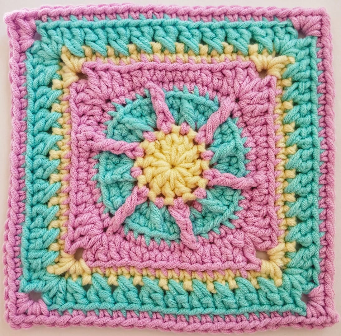 close up of the yellow, blue and pink granny square at round 9 of the written crochet pattern
