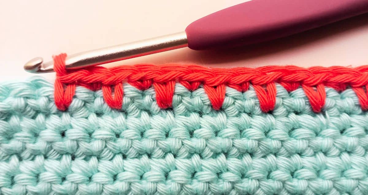 a row of single crochet spike stitches on a blue crochet fabric