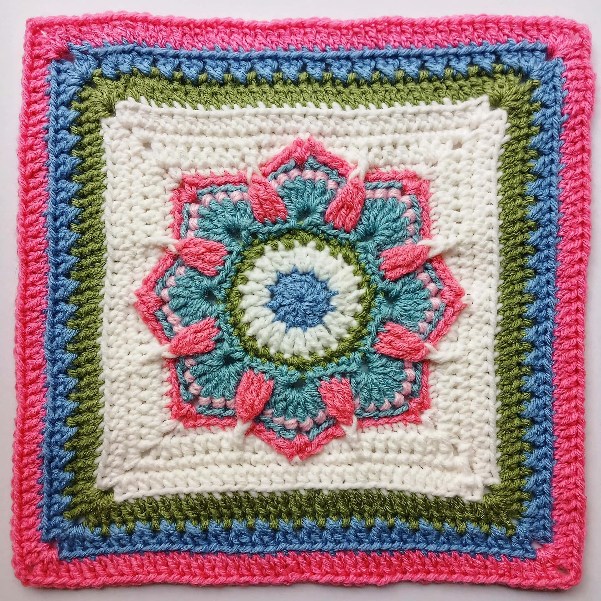 A croichet granny square with lotus style motif in the centre
